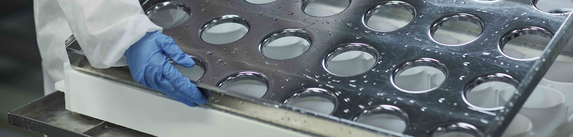 A worker holding a tin plated tray with holes